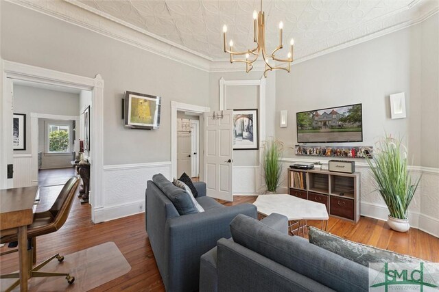 living room with crown molding, a chandelier, and hardwood / wood-style flooring