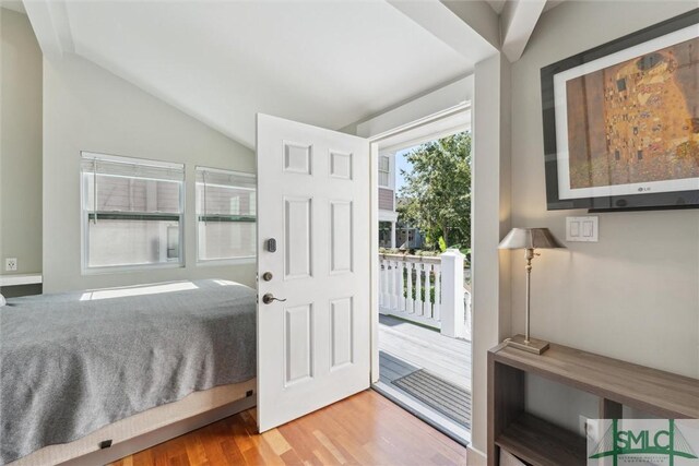 bedroom with light hardwood / wood-style floors, access to exterior, and vaulted ceiling