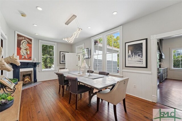 dining room with a high end fireplace, dark wood-type flooring, and a healthy amount of sunlight