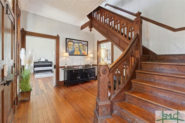 staircase with hardwood / wood-style flooring, a textured ceiling, and crown molding