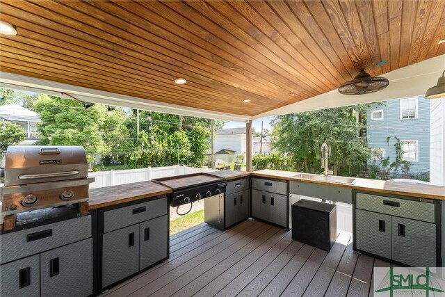 wooden deck with area for grilling, sink, and ceiling fan