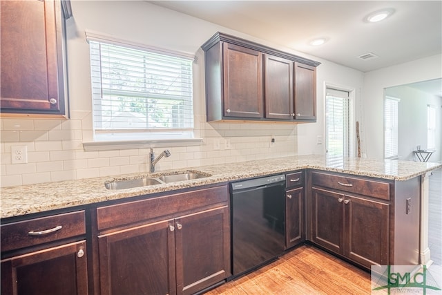 kitchen featuring sink, tasteful backsplash, black dishwasher, and light hardwood / wood-style floors