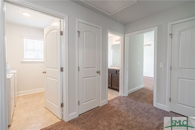 hall with washing machine and clothes dryer and light carpet