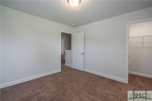 unfurnished bedroom featuring a walk in closet, a closet, and carpet floors