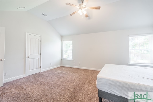 carpeted bedroom featuring ceiling fan, multiple windows, and lofted ceiling