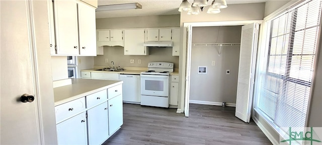 kitchen with hardwood / wood-style floors, sink, a notable chandelier, white appliances, and white cabinetry