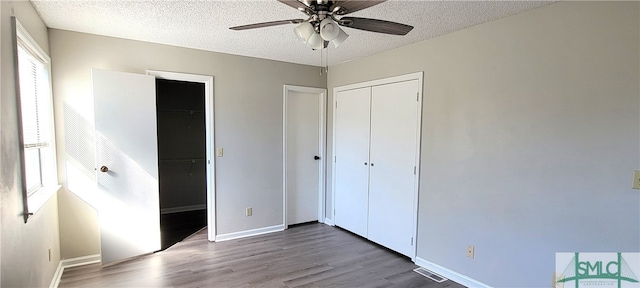 unfurnished bedroom with ceiling fan, wood-type flooring, a closet, and a textured ceiling