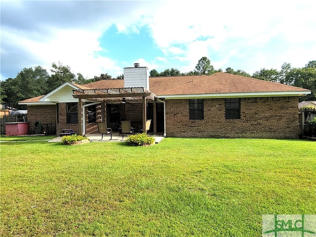 rear view of property with a yard, a pergola, and a patio area