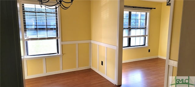 unfurnished room featuring hardwood / wood-style flooring and an inviting chandelier