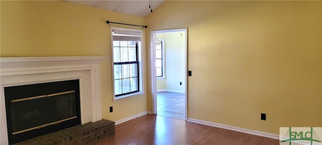 unfurnished living room with a fireplace, dark hardwood / wood-style flooring, and lofted ceiling