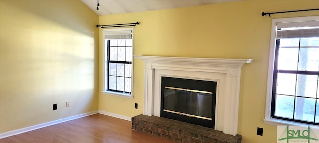 unfurnished living room featuring wood-type flooring, lofted ceiling, and a brick fireplace