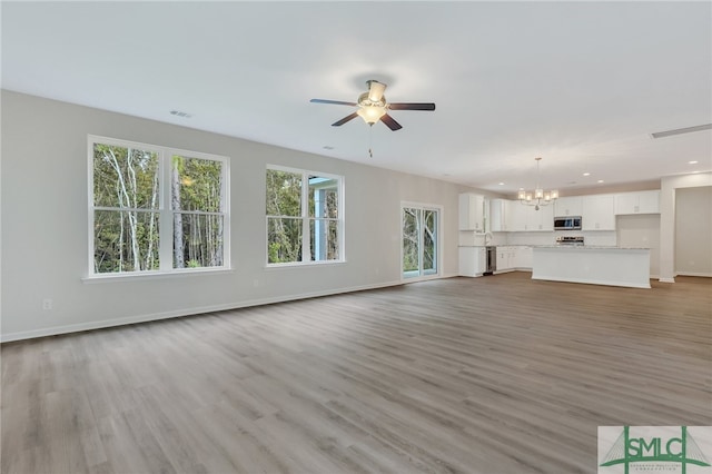 unfurnished living room with ceiling fan with notable chandelier and wood-type flooring