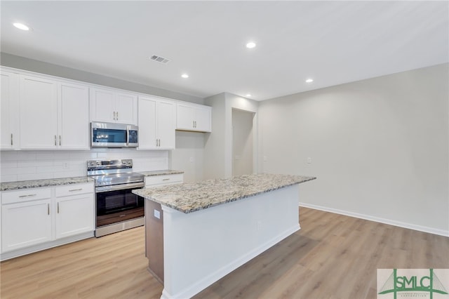 kitchen featuring light stone countertops, white cabinets, appliances with stainless steel finishes, and a kitchen island