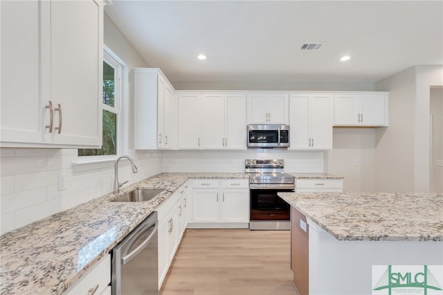 kitchen featuring light stone countertops, sink, stainless steel appliances, and white cabinetry