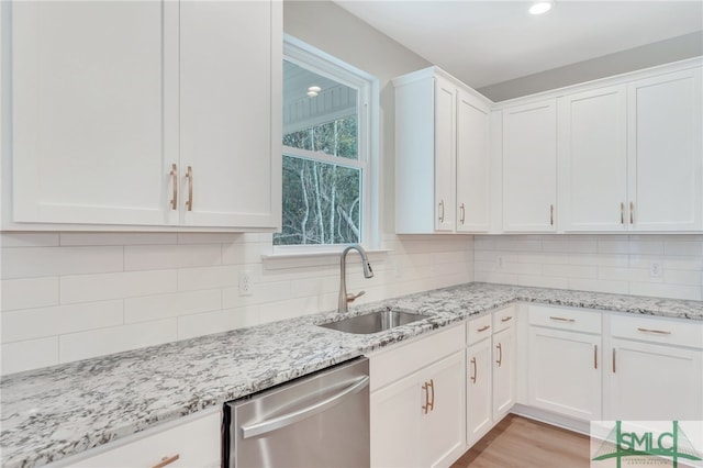 kitchen with decorative backsplash, dishwasher, sink, and white cabinetry