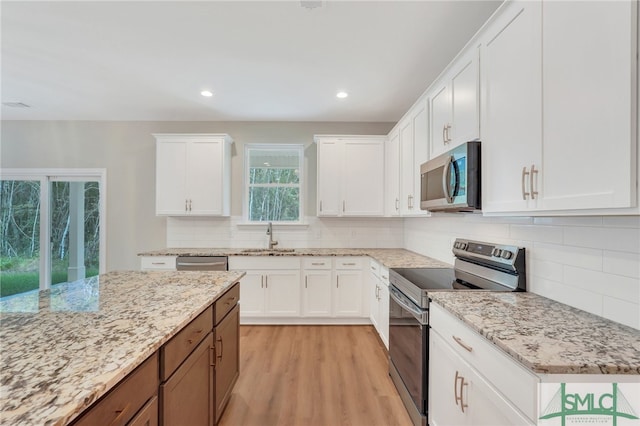 kitchen featuring light stone counters, white cabinetry, appliances with stainless steel finishes, and light hardwood / wood-style flooring