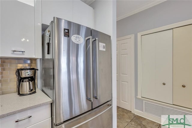 kitchen with white cabinetry, stainless steel refrigerator, tasteful backsplash, light stone counters, and light tile patterned floors