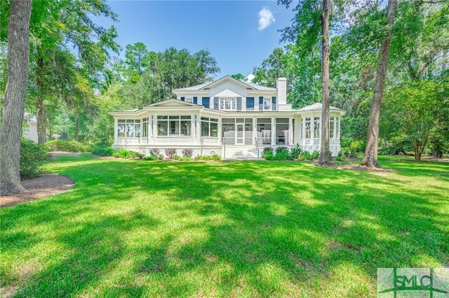 rear view of property featuring a sunroom and a yard