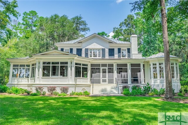 back of property featuring a lawn and a sunroom