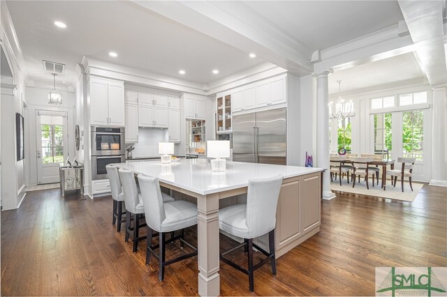 kitchen with dark hardwood / wood-style flooring, stainless steel appliances, a healthy amount of sunlight, white cabinetry, and a large island