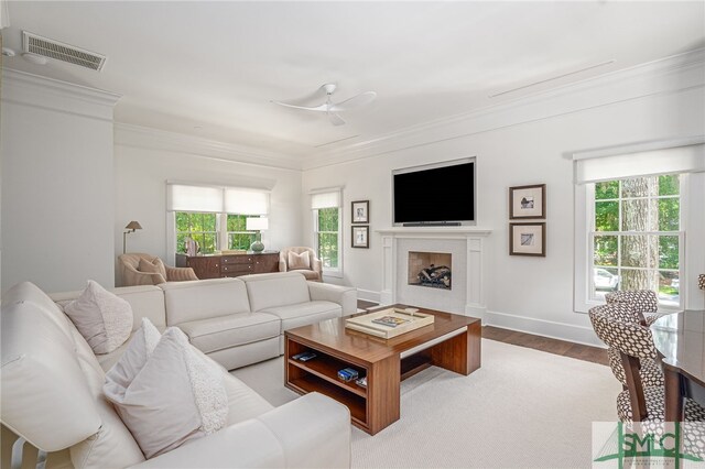 living room featuring light hardwood / wood-style flooring, ceiling fan, and crown molding