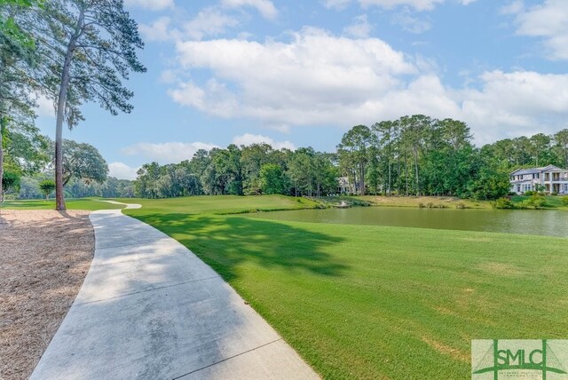 surrounding community with a water view and a lawn