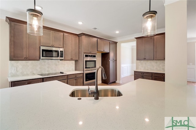 kitchen featuring sink, backsplash, appliances with stainless steel finishes, and hanging light fixtures