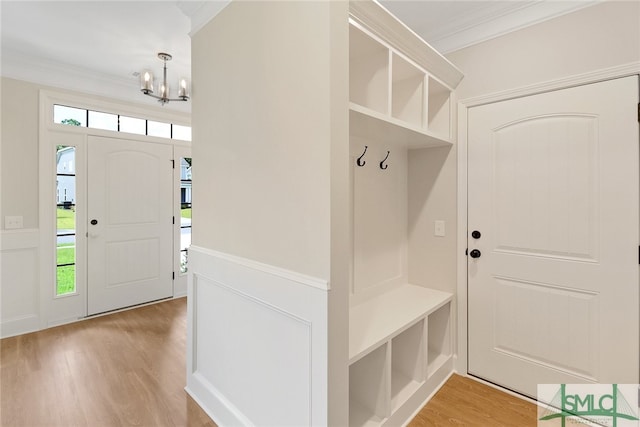 mudroom with light hardwood / wood-style flooring, crown molding, and a chandelier