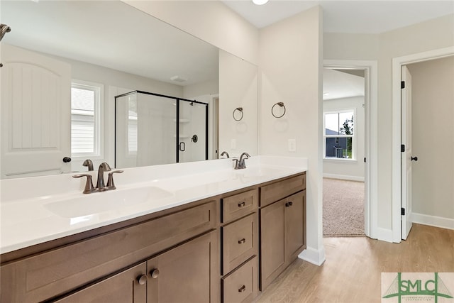 bathroom with walk in shower, dual vanity, and wood-type flooring