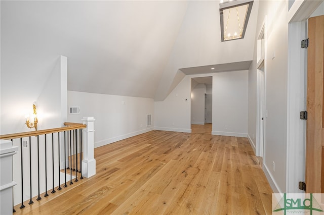 additional living space with hardwood / wood-style flooring, baseboards, visible vents, and vaulted ceiling