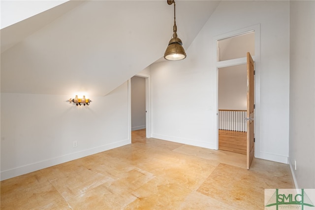 empty room with vaulted ceiling and baseboards