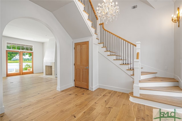 staircase featuring arched walkways, wood finished floors, visible vents, baseboards, and an inviting chandelier