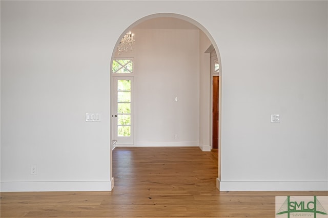 interior space featuring arched walkways, wood finished floors, and baseboards