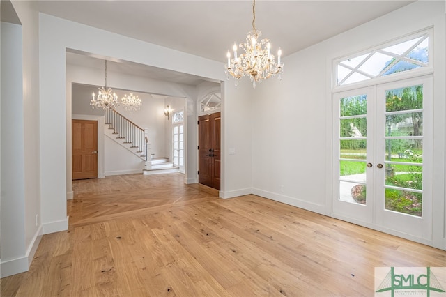 unfurnished dining area featuring baseboards, light wood-style floors, stairway, and a notable chandelier