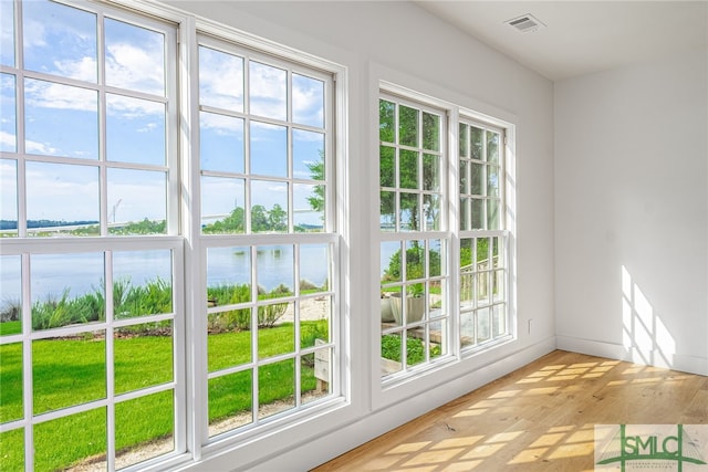 entryway featuring a wealth of natural light, a water view, visible vents, light wood-style floors, and baseboards