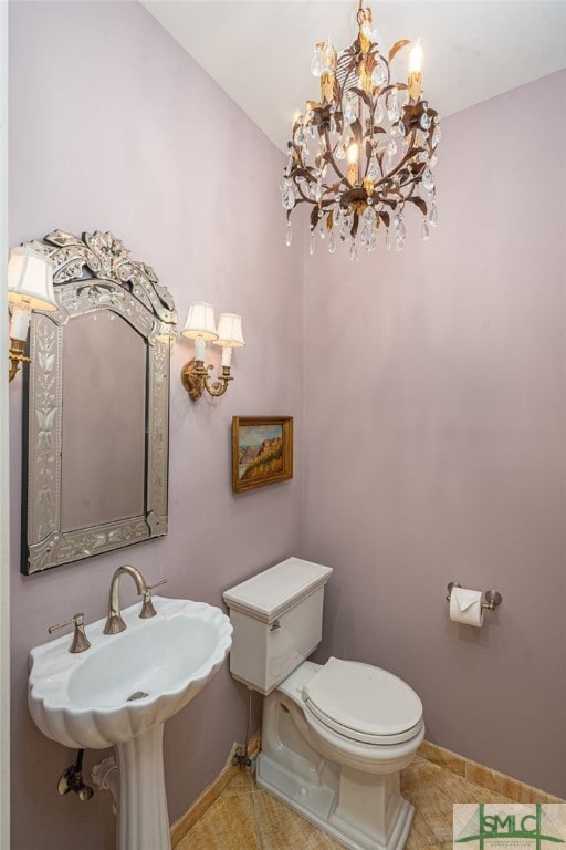 bathroom with baseboards, a sink, toilet, and tile patterned floors