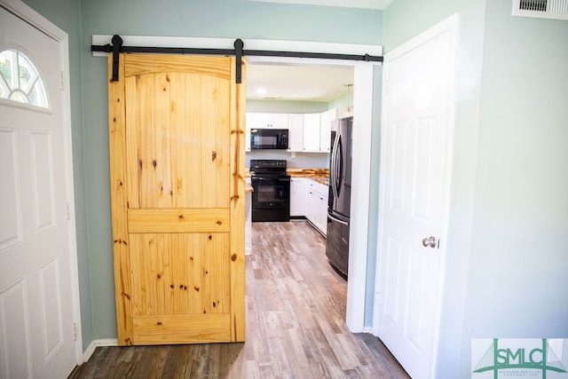 hall with light hardwood / wood-style floors and a barn door