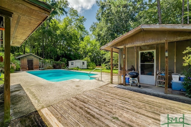 view of swimming pool with grilling area, a storage shed, and a wooden deck