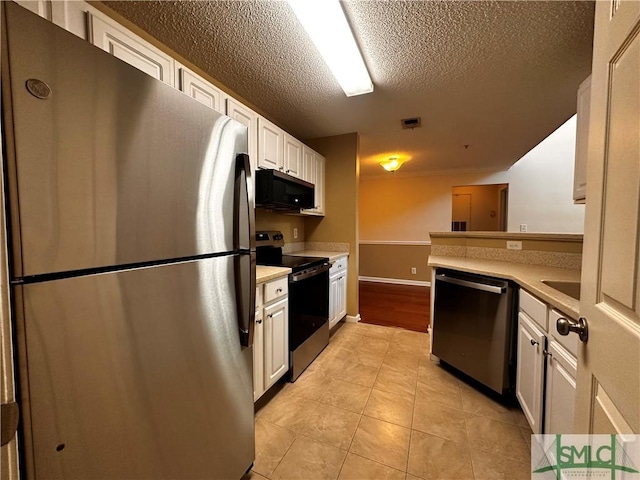 kitchen featuring white cabinets, light tile patterned flooring, stainless steel appliances, and a textured ceiling