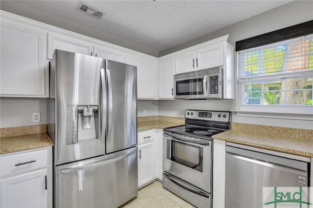 kitchen with white cabinets, light tile patterned floors, a textured ceiling, and appliances with stainless steel finishes