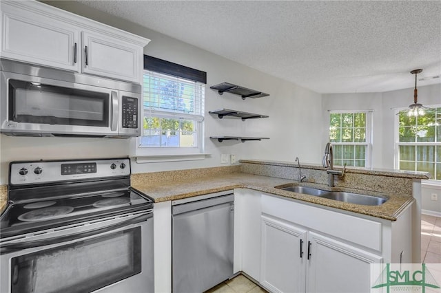 kitchen with sink, light tile patterned floors, a textured ceiling, appliances with stainless steel finishes, and white cabinetry