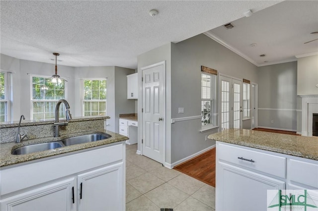 kitchen with white cabinetry, sink, pendant lighting, a textured ceiling, and light tile patterned floors