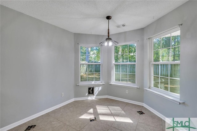 unfurnished dining area featuring light tile patterned floors and a textured ceiling