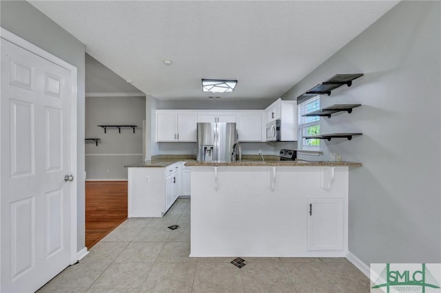 kitchen featuring kitchen peninsula, stainless steel refrigerator with ice dispenser, light tile patterned floors, and white cabinetry