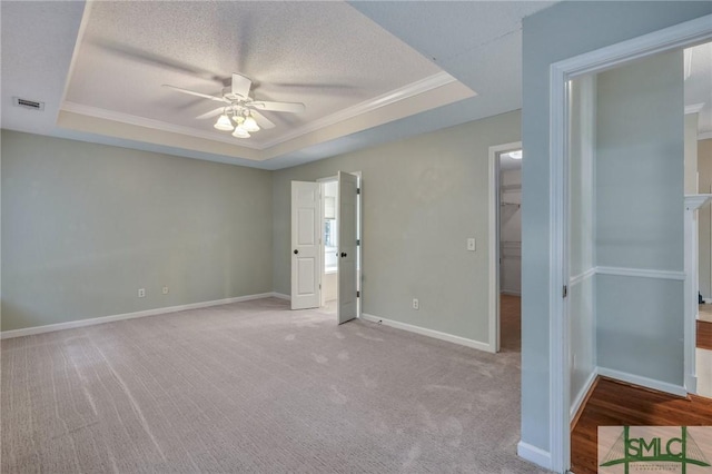 unfurnished bedroom featuring a raised ceiling, ceiling fan, a spacious closet, and a textured ceiling