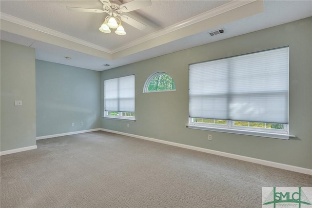 carpeted spare room featuring a textured ceiling, a raised ceiling, ceiling fan, and ornamental molding