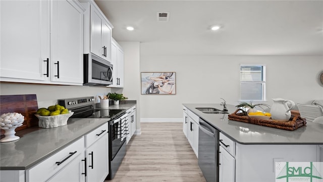 kitchen featuring light hardwood / wood-style floors, white cabinetry, sink, an island with sink, and stainless steel appliances