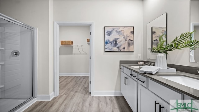 bathroom featuring hardwood / wood-style floors, a shower with door, and vanity