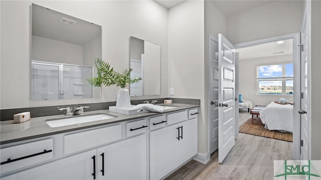 bathroom with wood-type flooring, a shower with door, and vanity