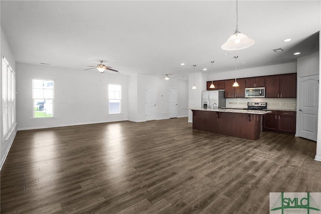 kitchen with tasteful backsplash, dark wood-style floors, a breakfast bar, open floor plan, and stainless steel appliances